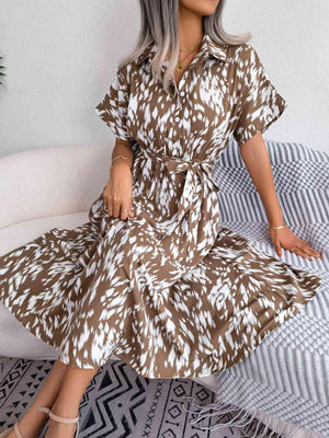 a woman sitting on a bed wearing a brown and white dress