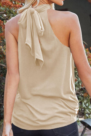 a woman wearing a tan top with a tie around her neck