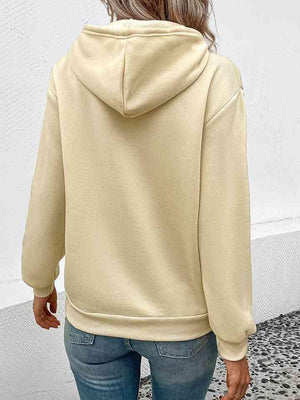 a woman wearing a beige hoodie and jeans