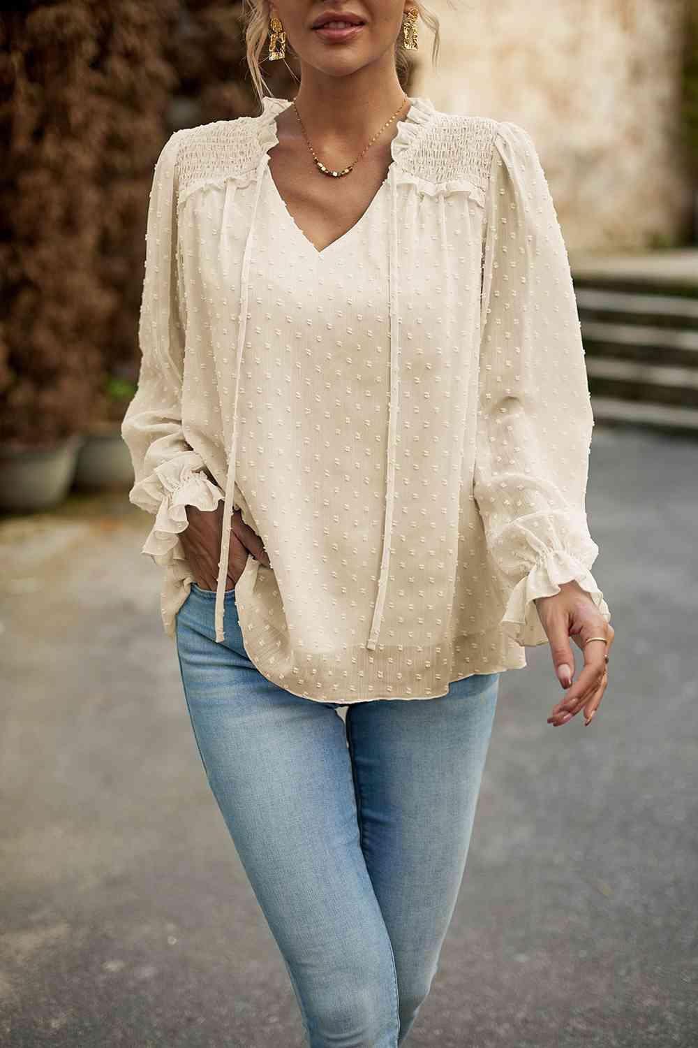 a woman wearing a white blouse and jeans