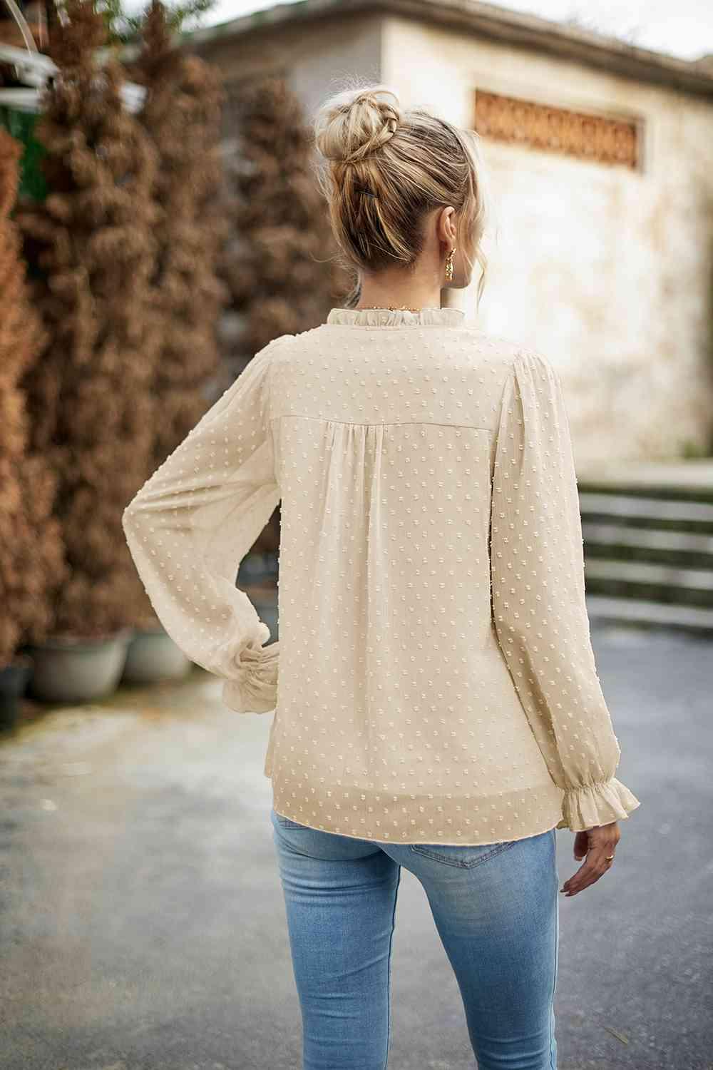 a woman in jeans and a blouse is standing outside