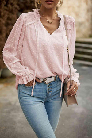 a woman wearing a pink blouse and jeans