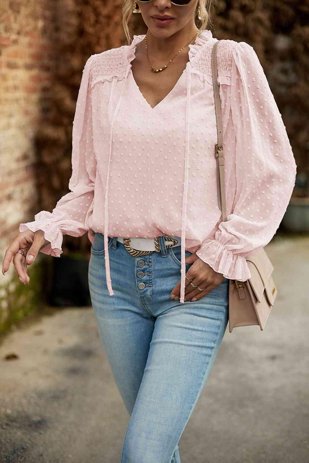 a woman wearing a pink blouse and jeans