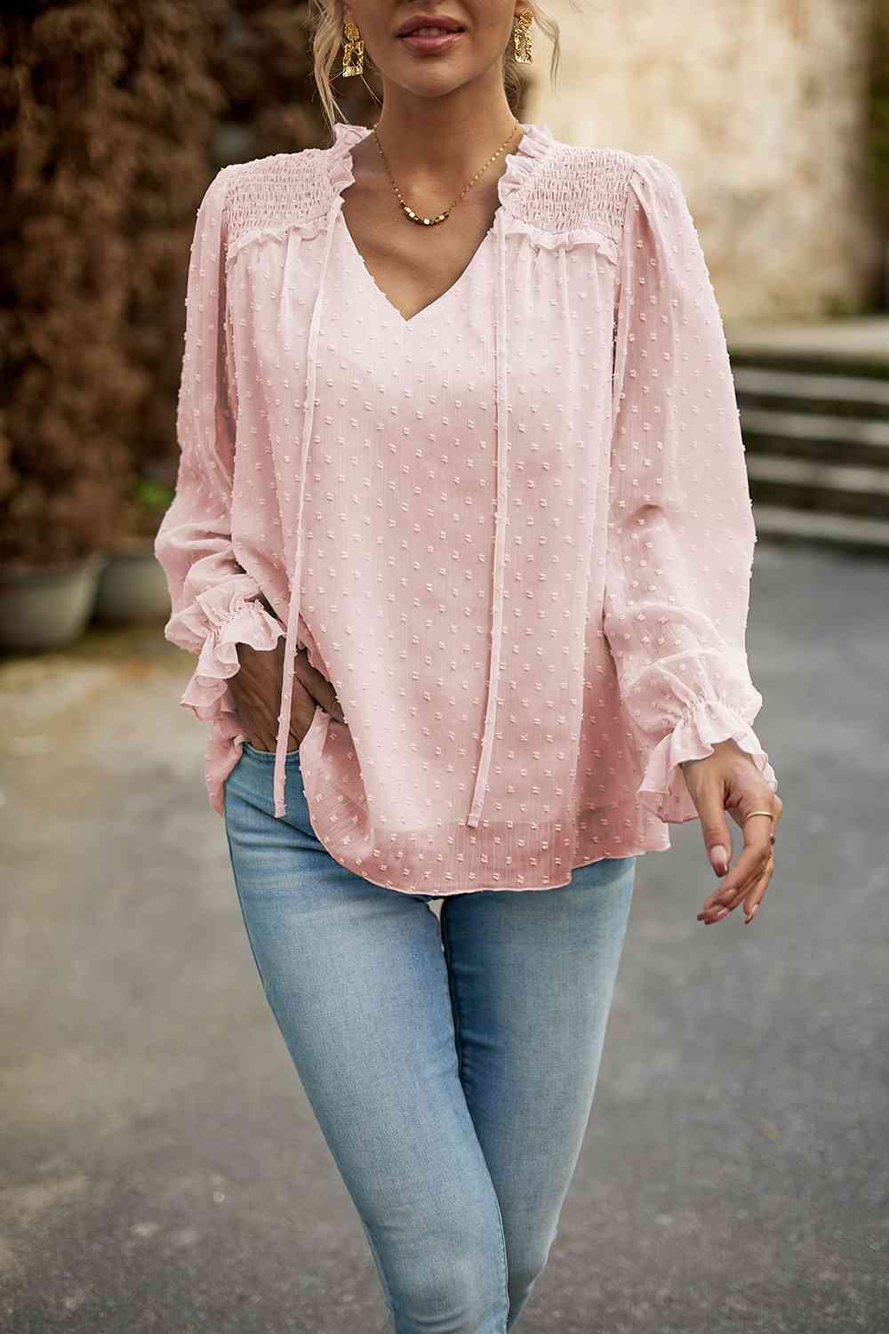 a woman wearing a pink blouse and jeans