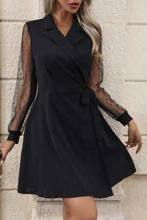 a woman wearing a black dress with sheer sleeves