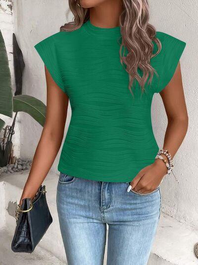 a woman wearing a green top and jeans