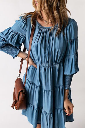 a woman in a blue dress holding a brown purse