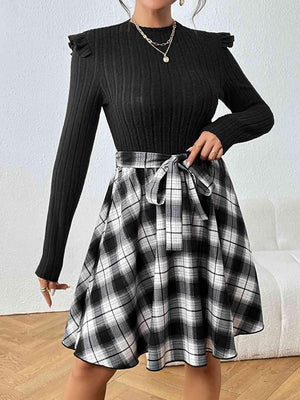 a woman in a black sweater and plaid skirt