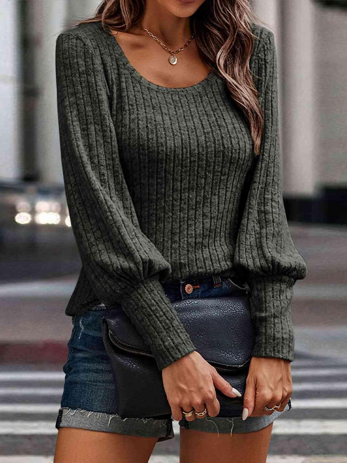 a woman wearing a green sweater and denim shorts