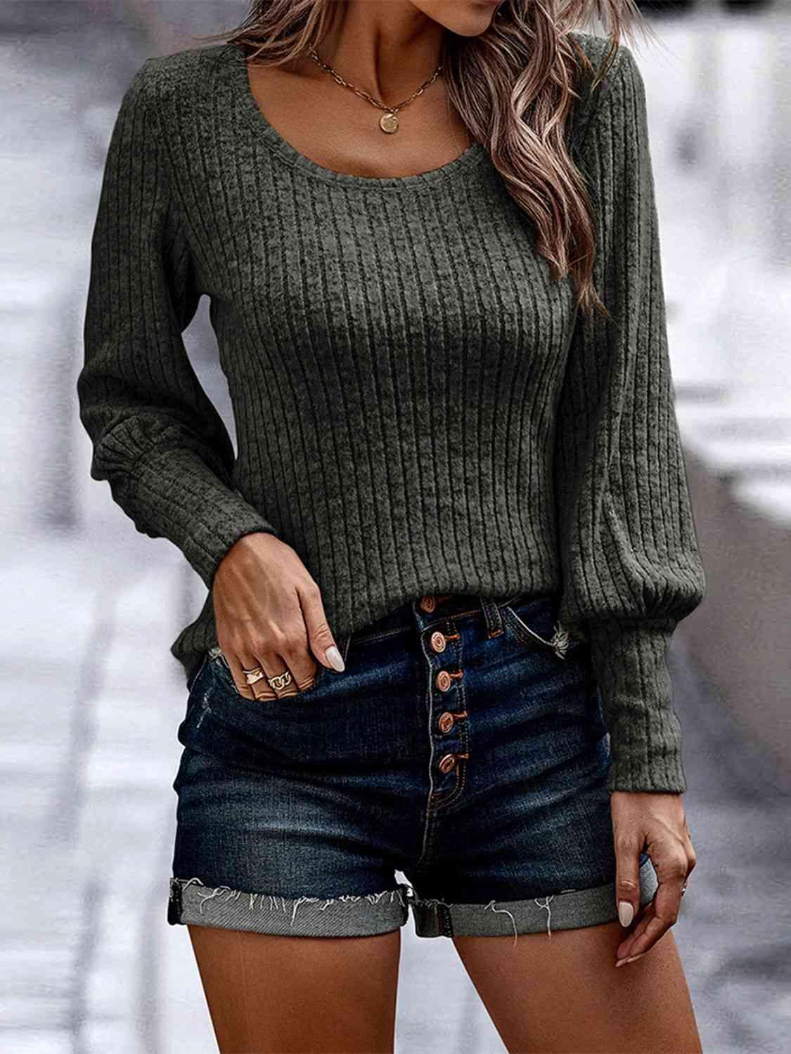 a woman wearing a green sweater and denim shorts