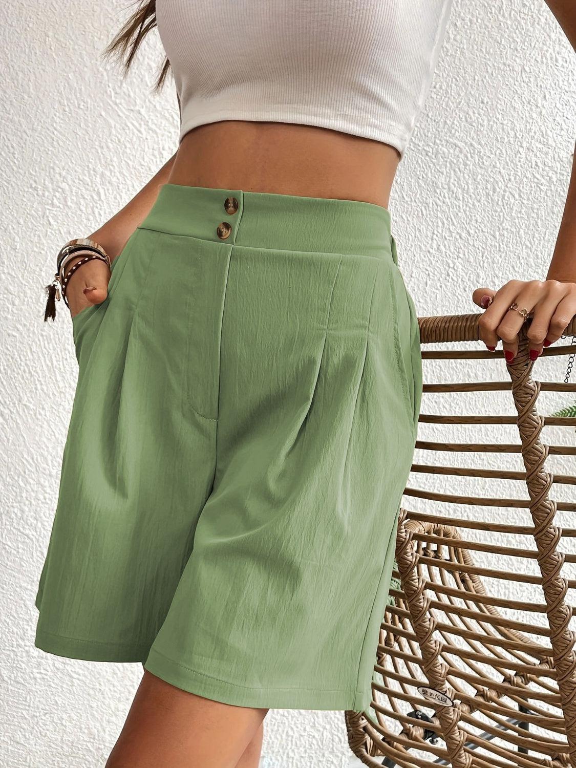 a woman in a white top and green shorts