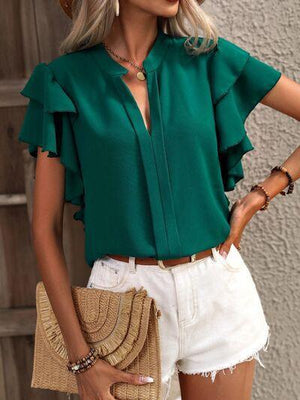 a woman wearing a green blouse and white shorts