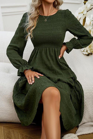 a woman sitting on a couch wearing a green dress
