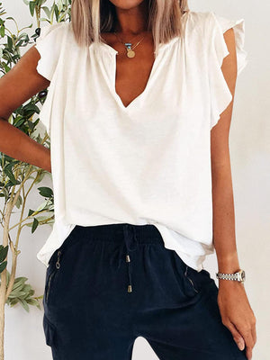 a woman standing next to a plant wearing a white top