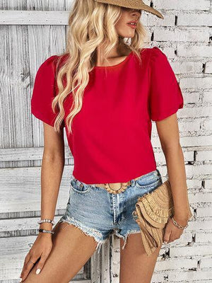 a woman wearing a red top and denim shorts