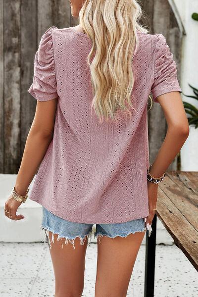 a woman wearing a pink sweater and denim shorts