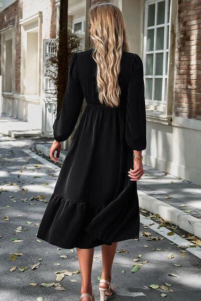 a woman in a black dress walking down a street