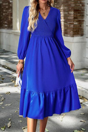 a woman in a blue dress standing on a sidewalk