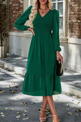 a woman in a green dress standing on a sidewalk