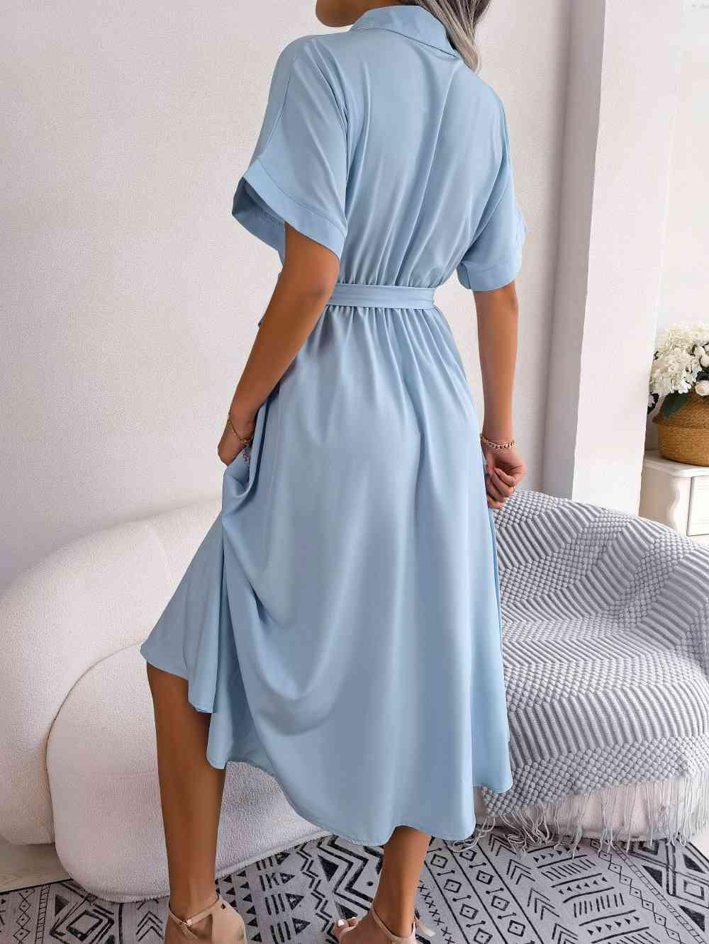 a woman in a blue dress standing in front of a bed