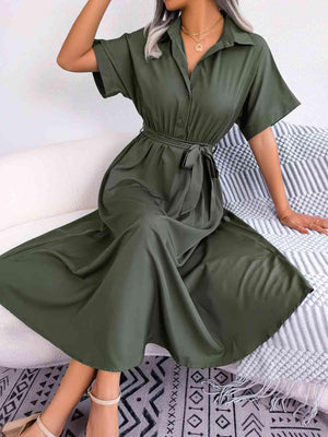 a woman sitting on a bed wearing a green dress