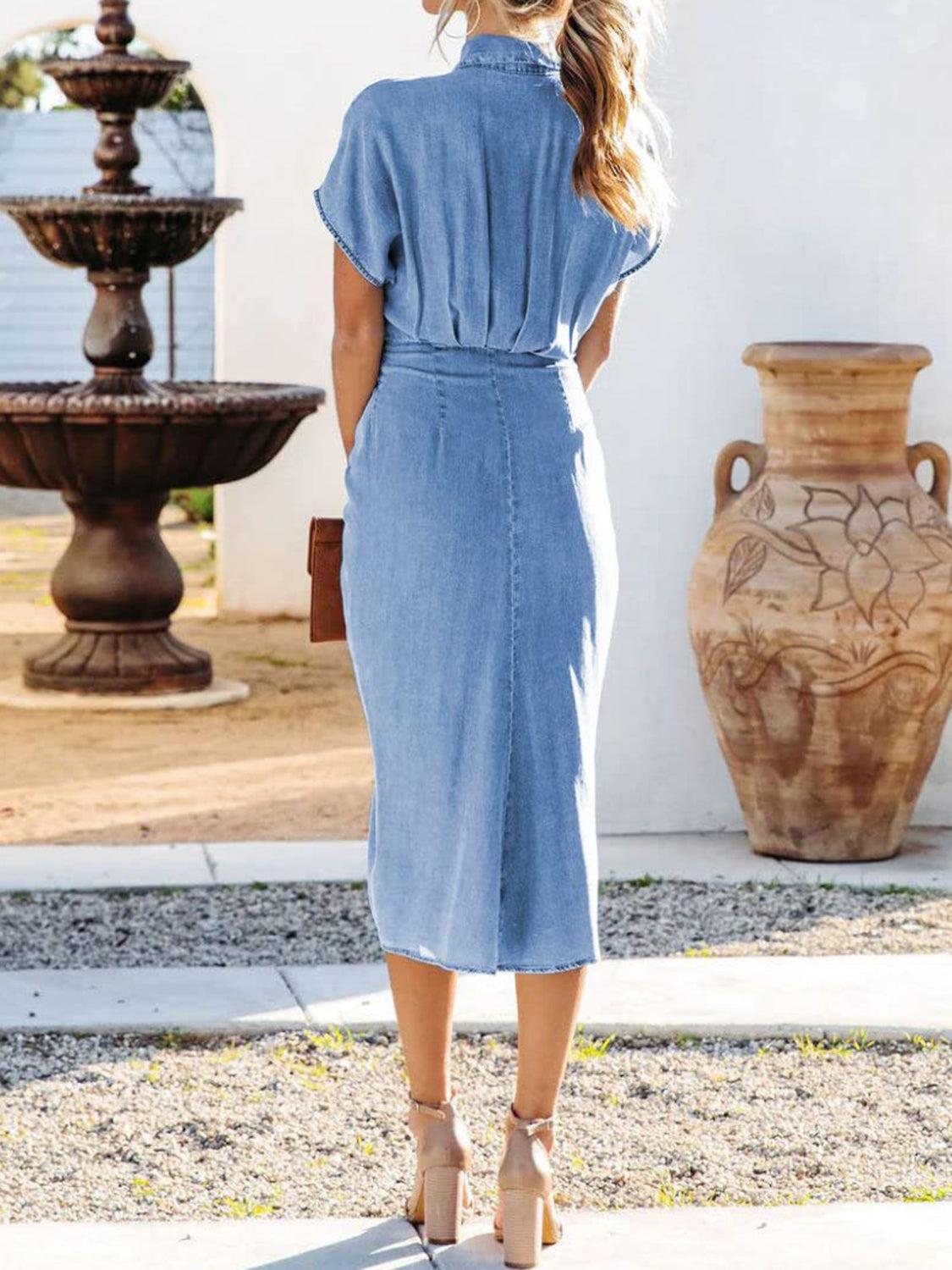 a woman in a denim dress standing in front of a fountain