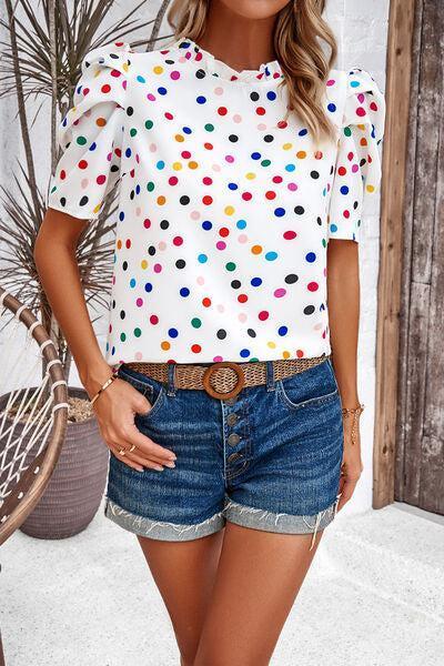 a woman wearing a polka dot top and denim shorts