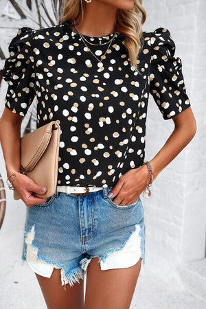 a woman wearing a polka dot top and denim shorts