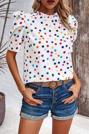 a woman wearing a polka dot top and denim shorts