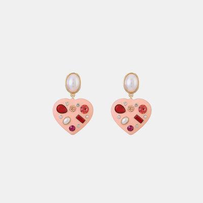 a pair of heart shaped earrings with pearls
