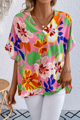 a woman wearing a colorful top and white pants