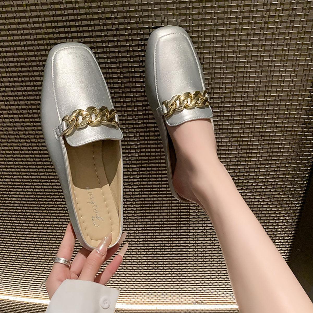 a woman's hand holding onto a pair of silver shoes