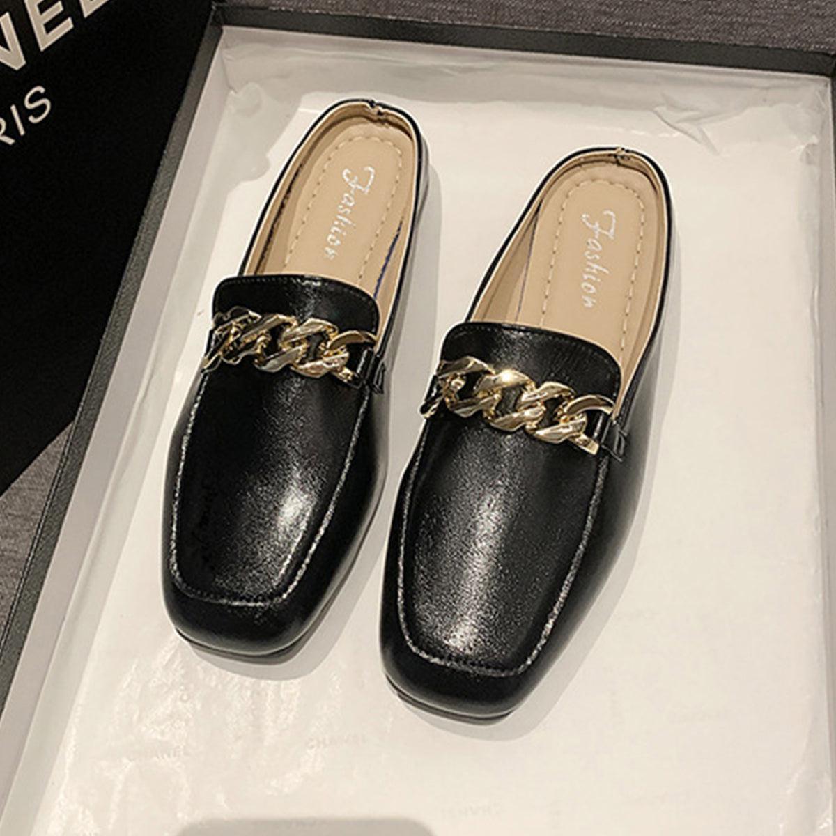 a pair of black loafers with a gold chain