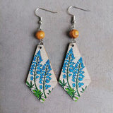 a pair of wooden earrings with blue flowers on them