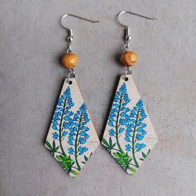 a pair of wooden earrings with blue flowers on them