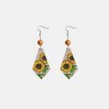 a pair of earrings with sunflowers on them