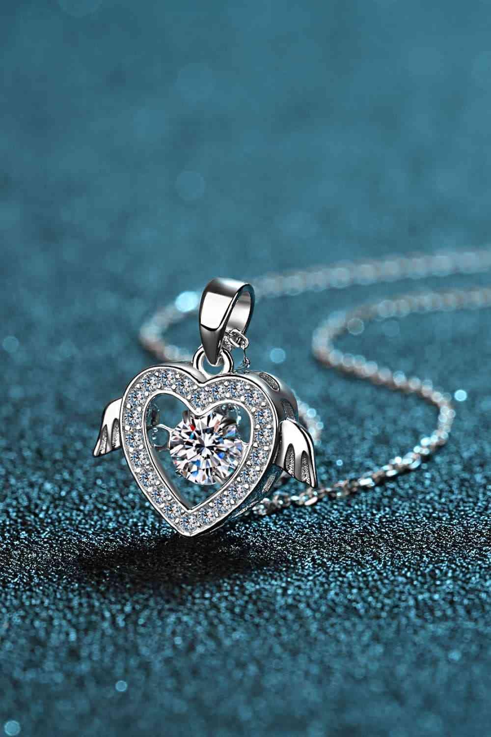 a heart shaped necklace with angel wings on a blue background