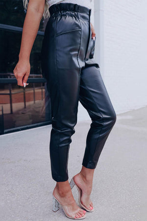 a woman wearing black leather pants and heels