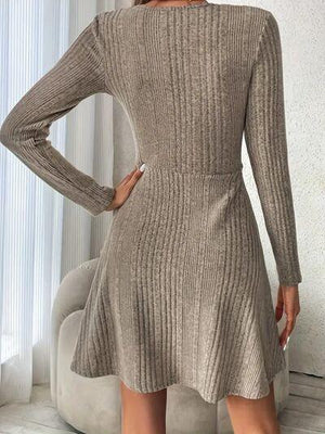 a woman standing in a room wearing a sweater dress