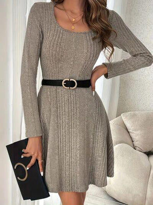 a woman wearing a gray sweater dress with a black purse