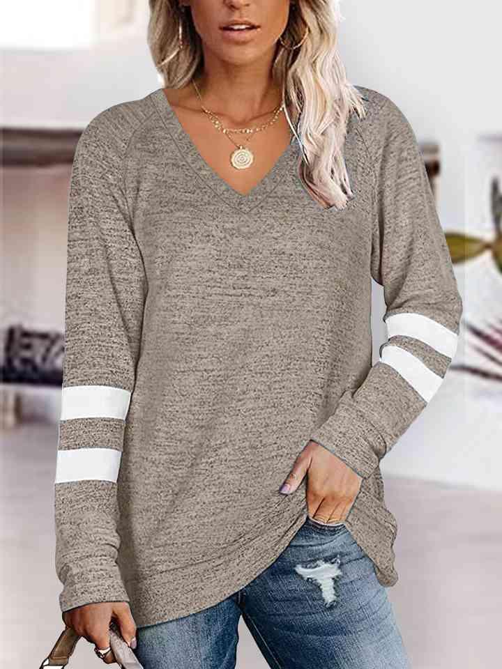 a woman wearing a grey sweater and ripped jeans