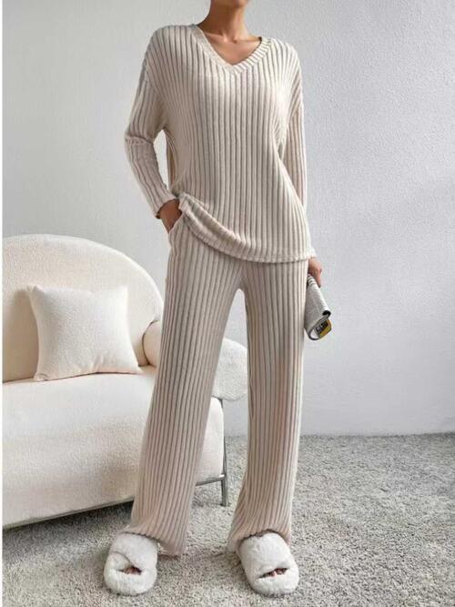 a woman standing in a room wearing a sweater and pants