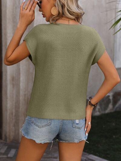 a woman wearing a green sweater and denim shorts