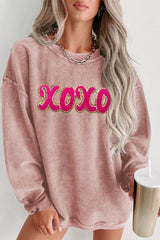 a woman wearing a pink sweater with the word boo on it