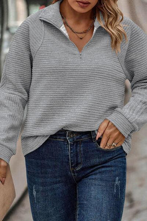 a woman wearing a grey sweater and jeans