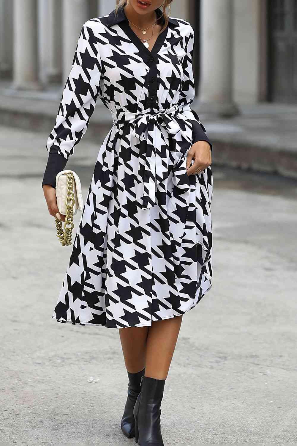 a woman in a black and white dress is walking down the street