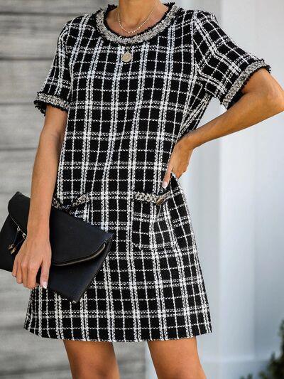 a woman in a black and white dress holding a black purse