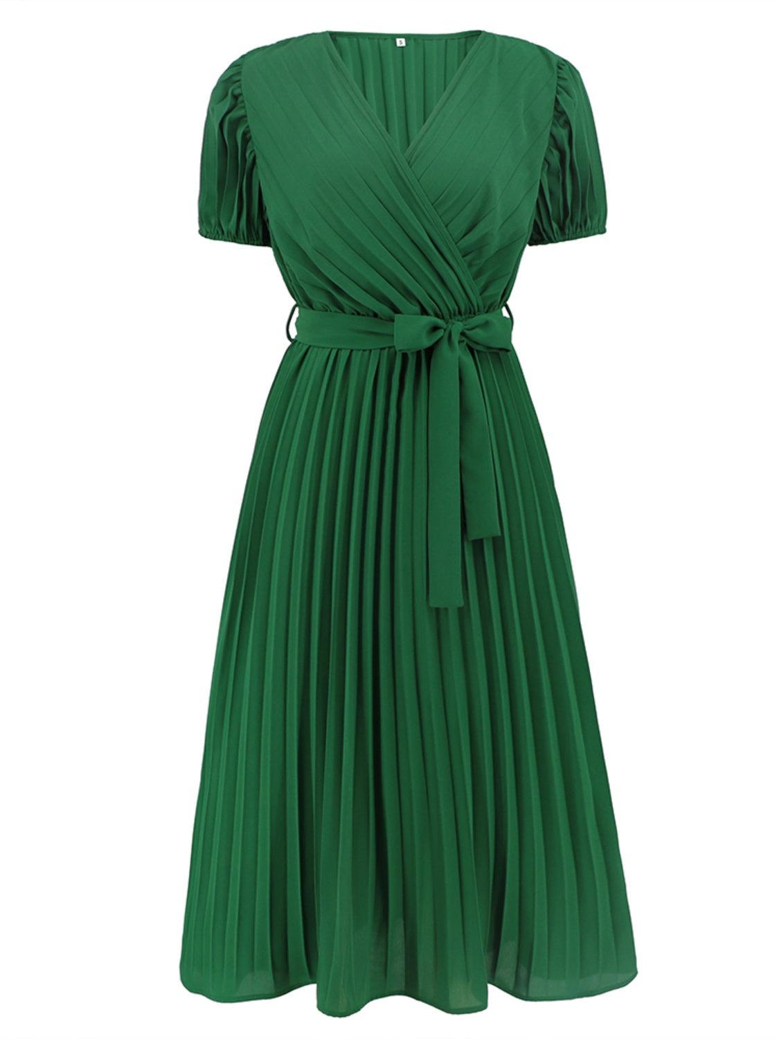 a woman wearing a green dress with a tie around the waist