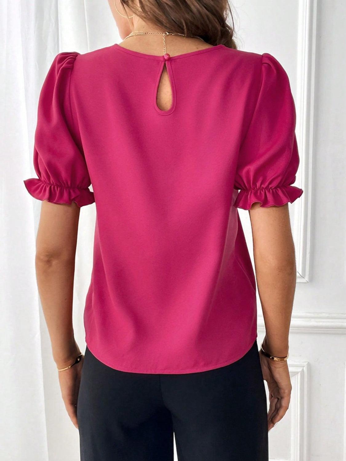 a woman wearing a pink blouse and black pants