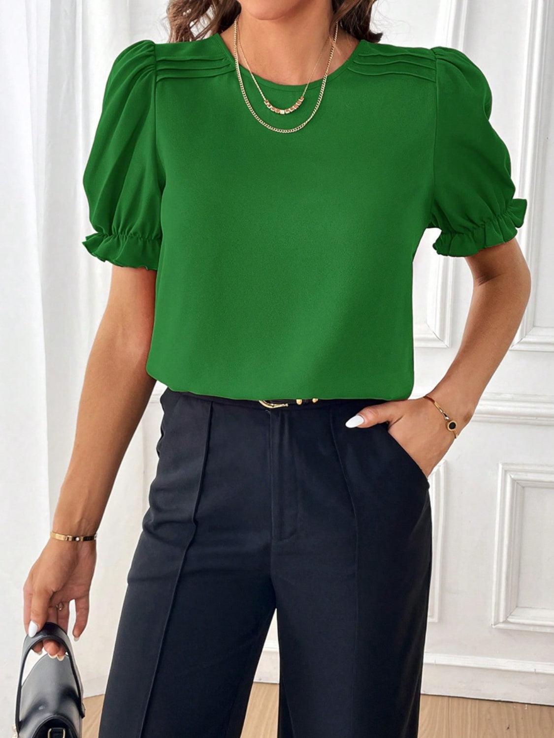 a woman wearing a green top and black pants